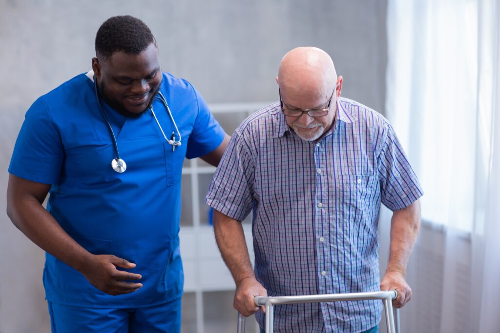 Caregiver,Is,Teaching,Old,Man,To,Walk,With,Walker.,Professional